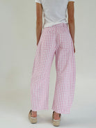 Person wearing pink checkered barrel pants on a plain background from back