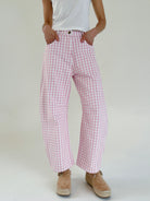 Person wearing pink checkered pants and a white top on a plain background