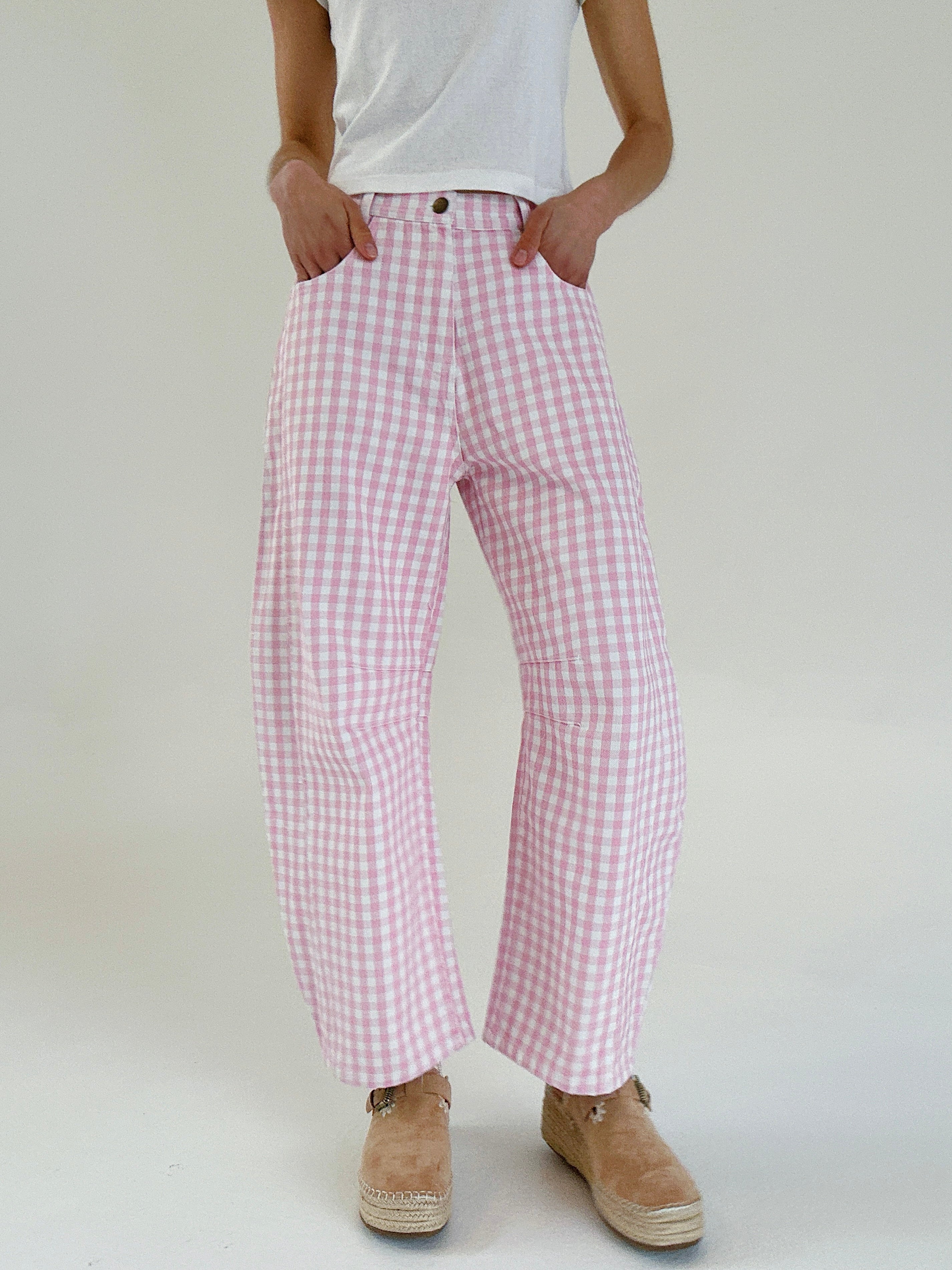 Person wearing pink checkered pants and a white top on a plain background