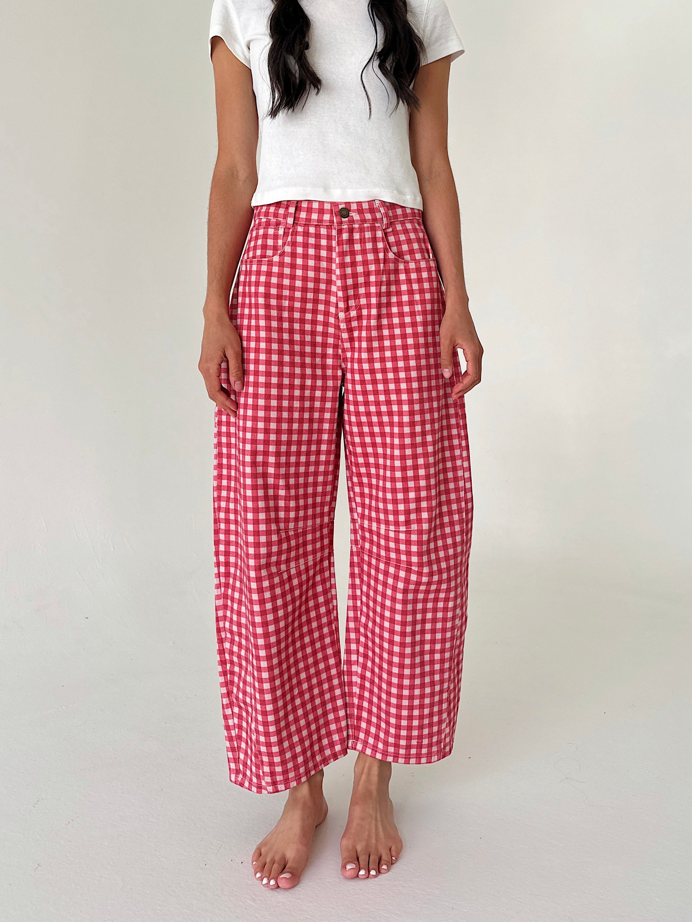 A person wearing red and white gingham wide-leg cropped pants with a white t-shirt, standing barefoot against a plain off-white studio background.
