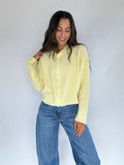 Woman wearing a light yellow shirt and blue jeans against a white background