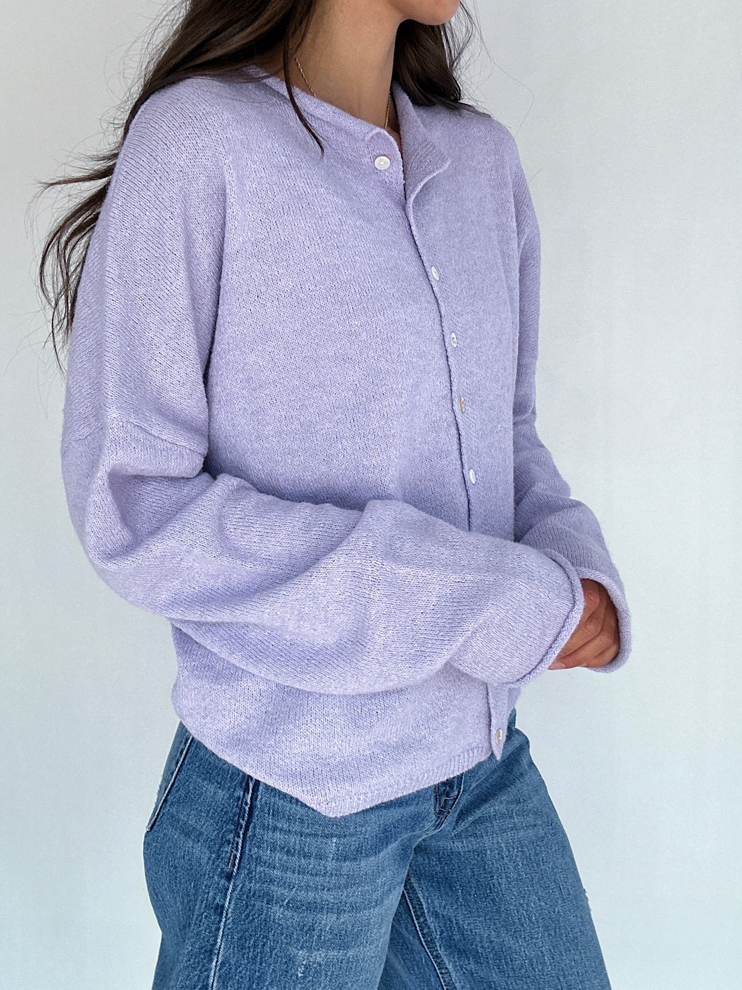 Person wearing a light purple button-up shirt and blue jeans against a white background