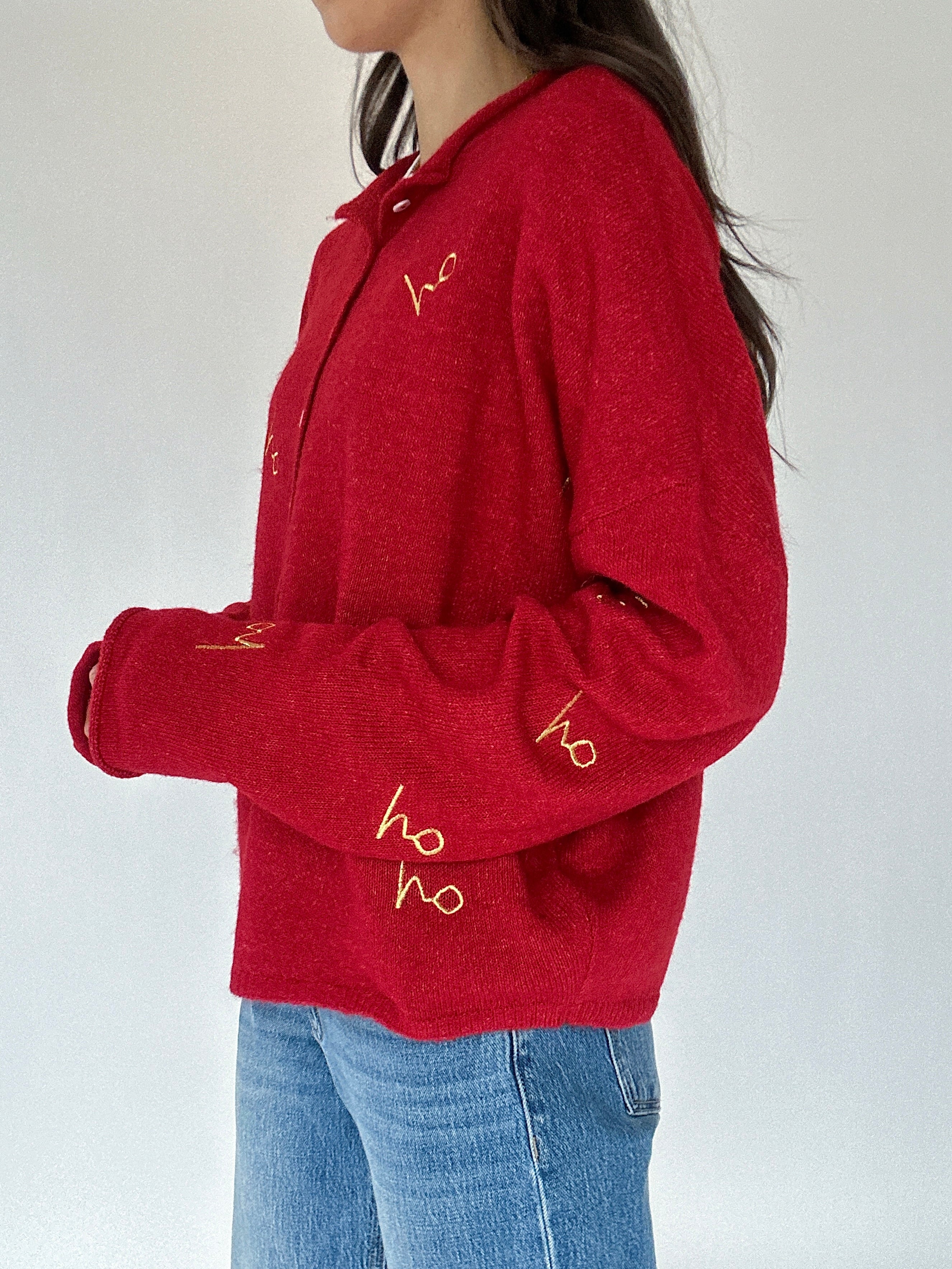 Red cardigan with gold 'ho ho ho' embroidered text worn by a person on a white background showing side