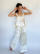 Woman wearing a matching top and pants set with floral patterns against a white background