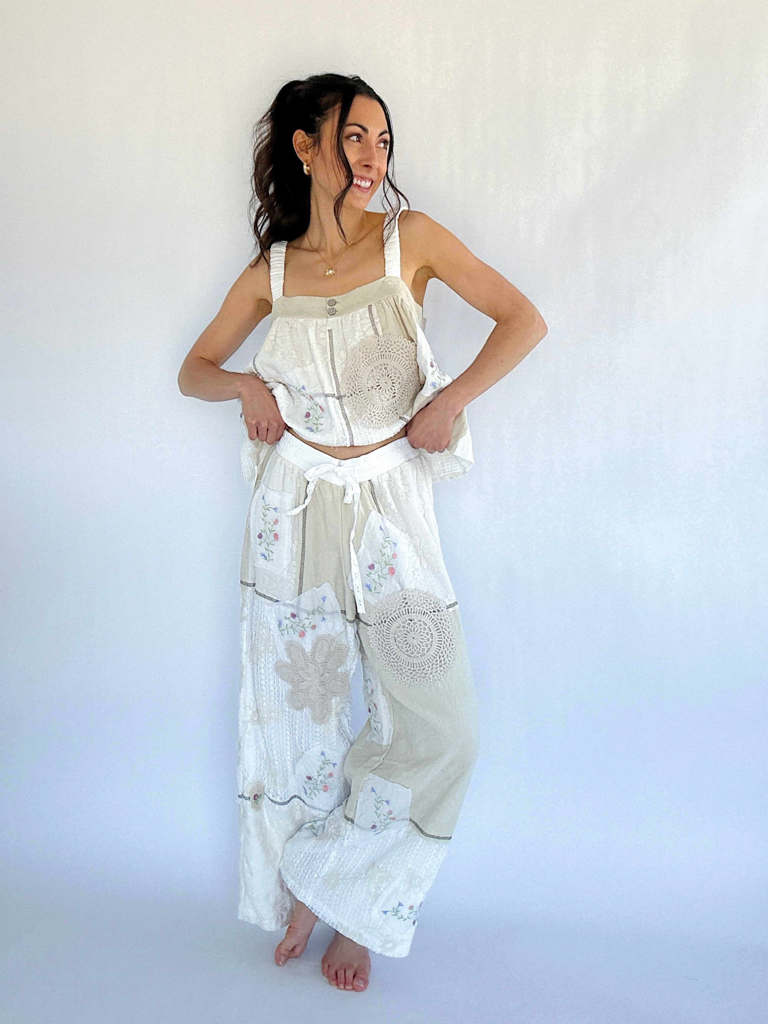 Woman wearing a white embroidered top and matching pants against a white background
