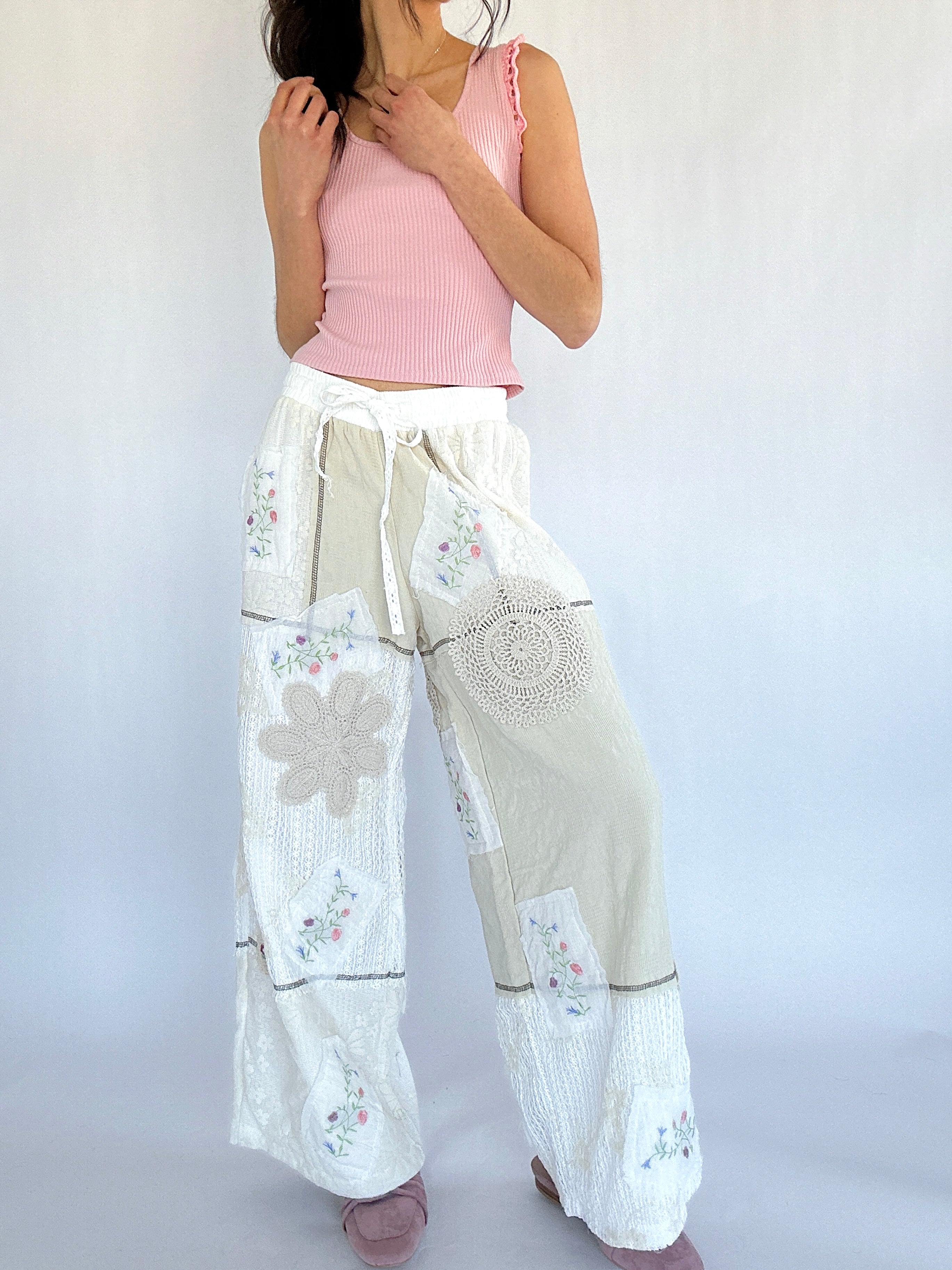 Woman wearing a pink top and white floral pants on a plain background