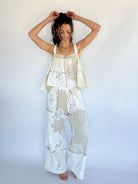 Woman wearing a beige and white floral pajama set against a plain background