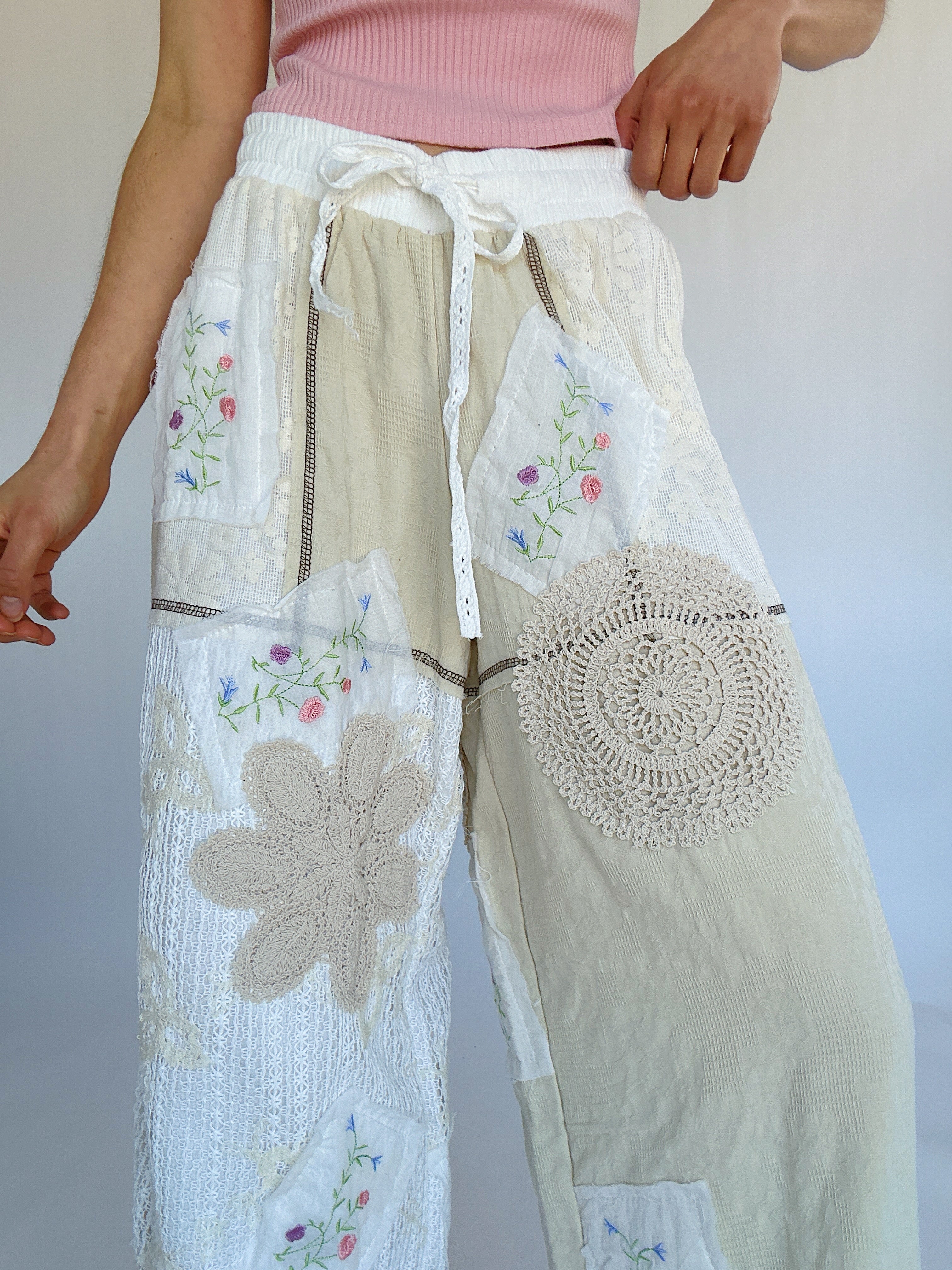 Person wearing a pair of wide-leg pants with floral and geometric embroidery on a plain background showing the elastic/drawstring waistband