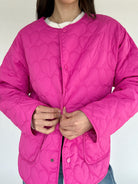 Person wearing a pink quilted jacket on a plain background with snap front