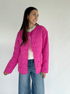 Woman wearing a pink quilted jacket against a white background