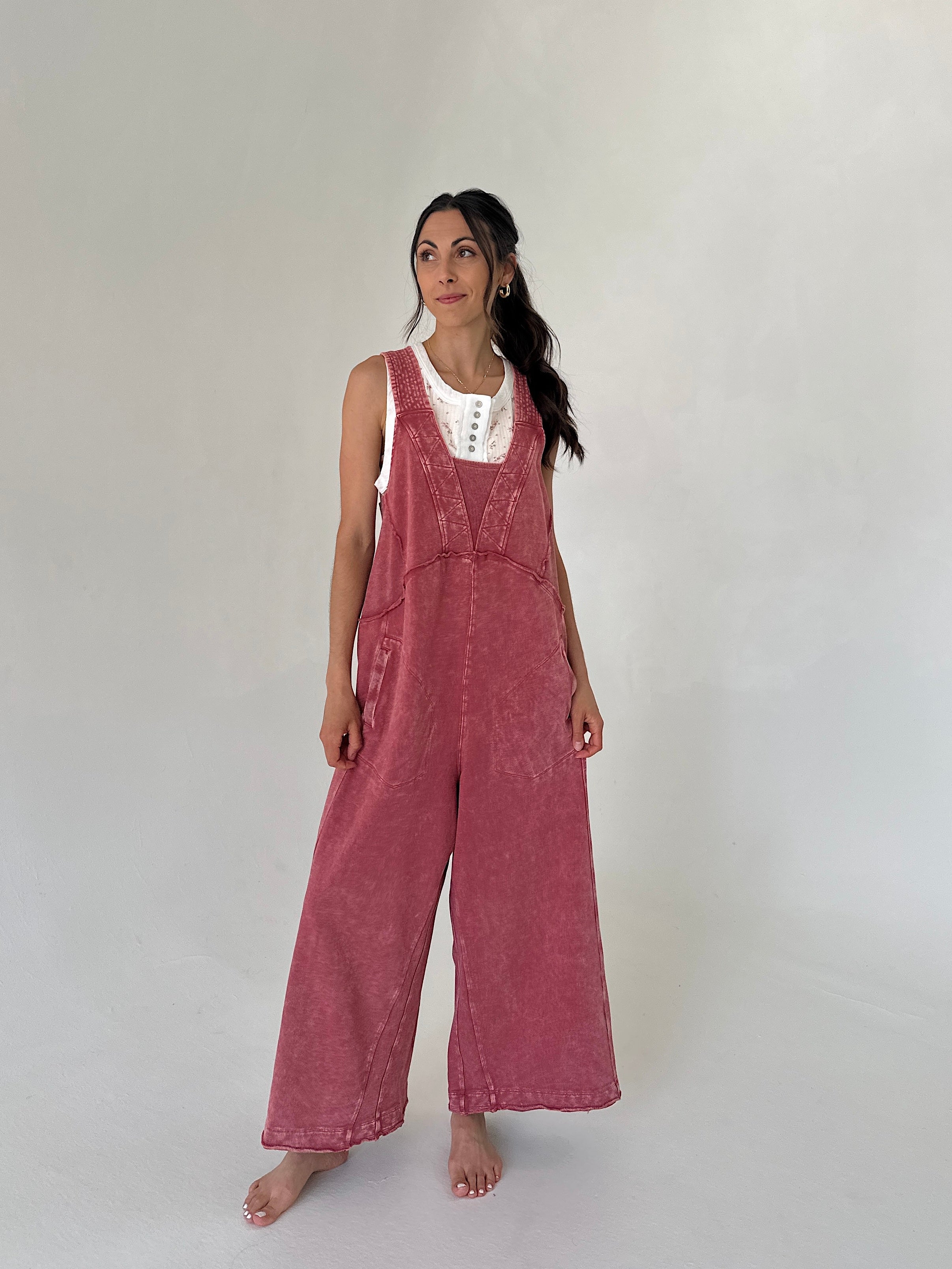 Woman wearing a pink terry knit jumpsuit against a white background