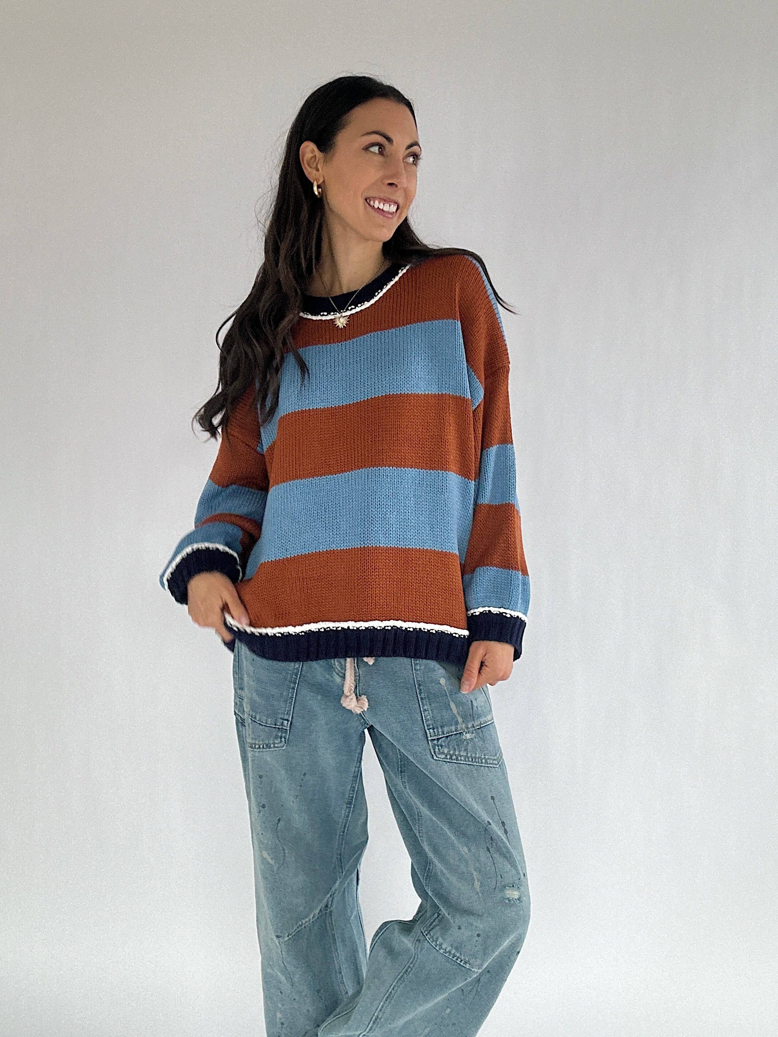 Woman wearing a striped sweater and jeans against a plain background