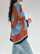 Person wearing a brown and blue striped sweater with a white background from side