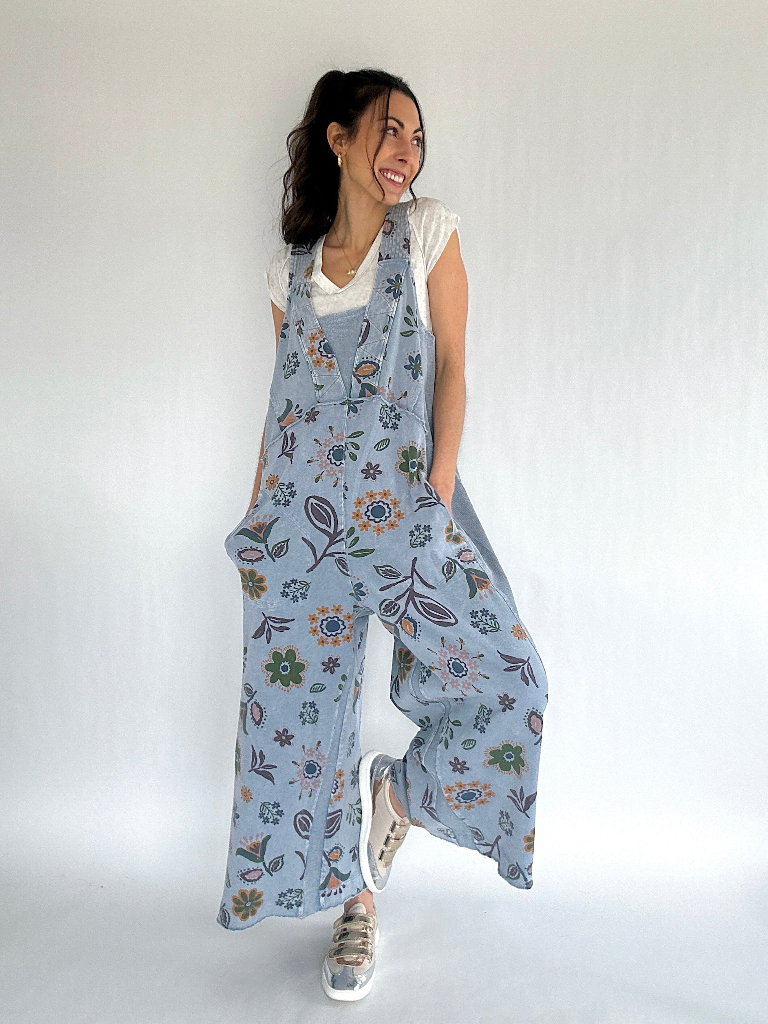 Woman wearing a floral patterned blue jumpsuit against a white background