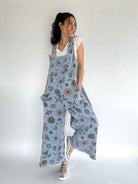 Woman wearing a floral patterned blue jumpsuit against a white background