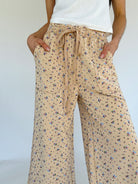 Beige floral pants worn by a person on a white background