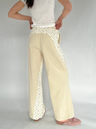 Beige pants with floral detailing worn by a person on a plain background showing back