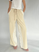 Beige pants with floral detailing on a plain background