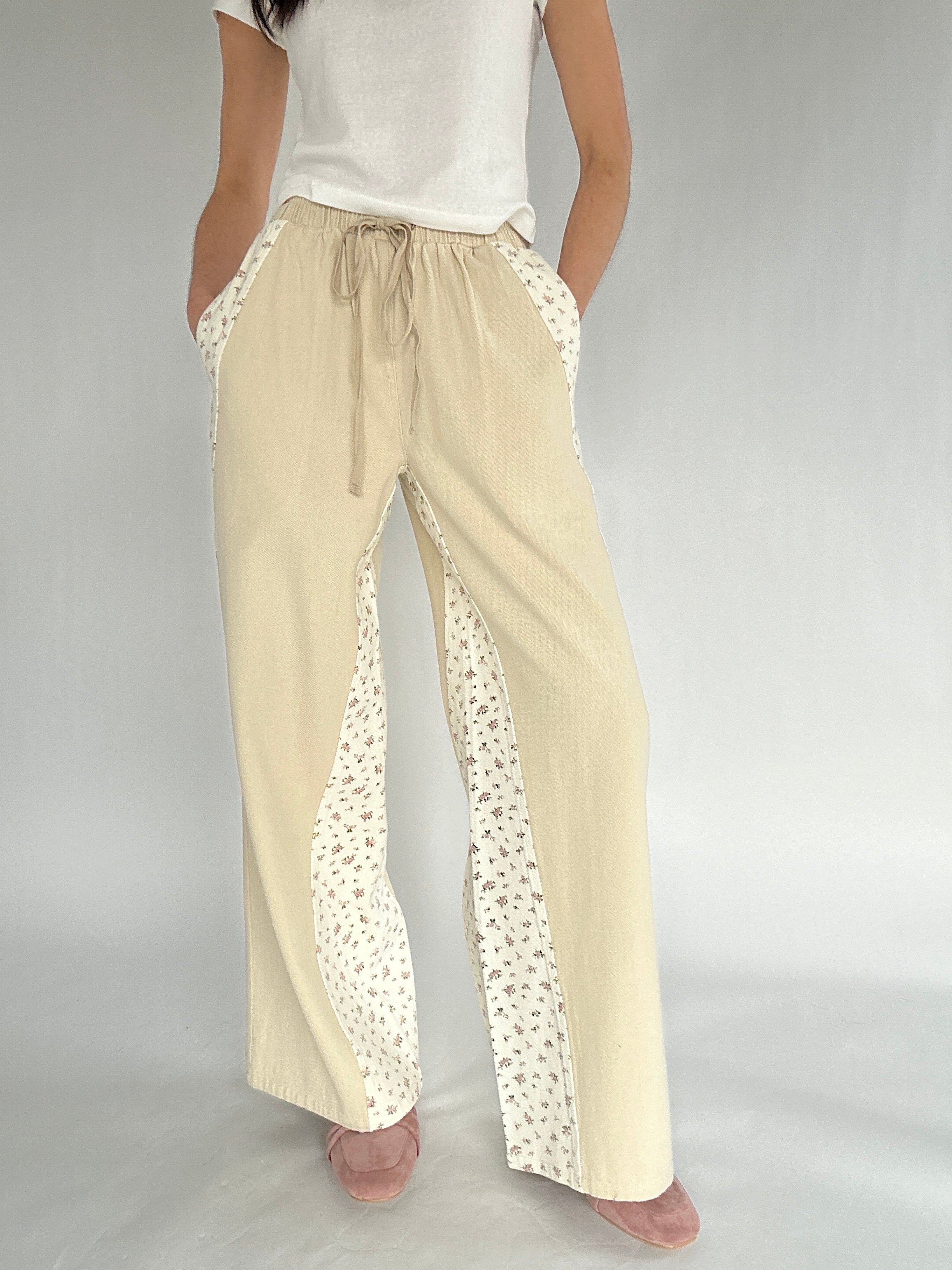 Beige pants with floral detailing on a plain background