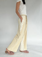 Person wearing beige pants with floral  pattern on a plain background showing side with pockets