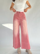 Person wearing pink corduroy wide-leg pants and a white top on a plain background