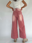 Person wearing pink corduroy wide-leg pants and a white top on a plain background