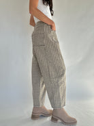 Person wearing plaid pants and beige boots on a plain background to show side