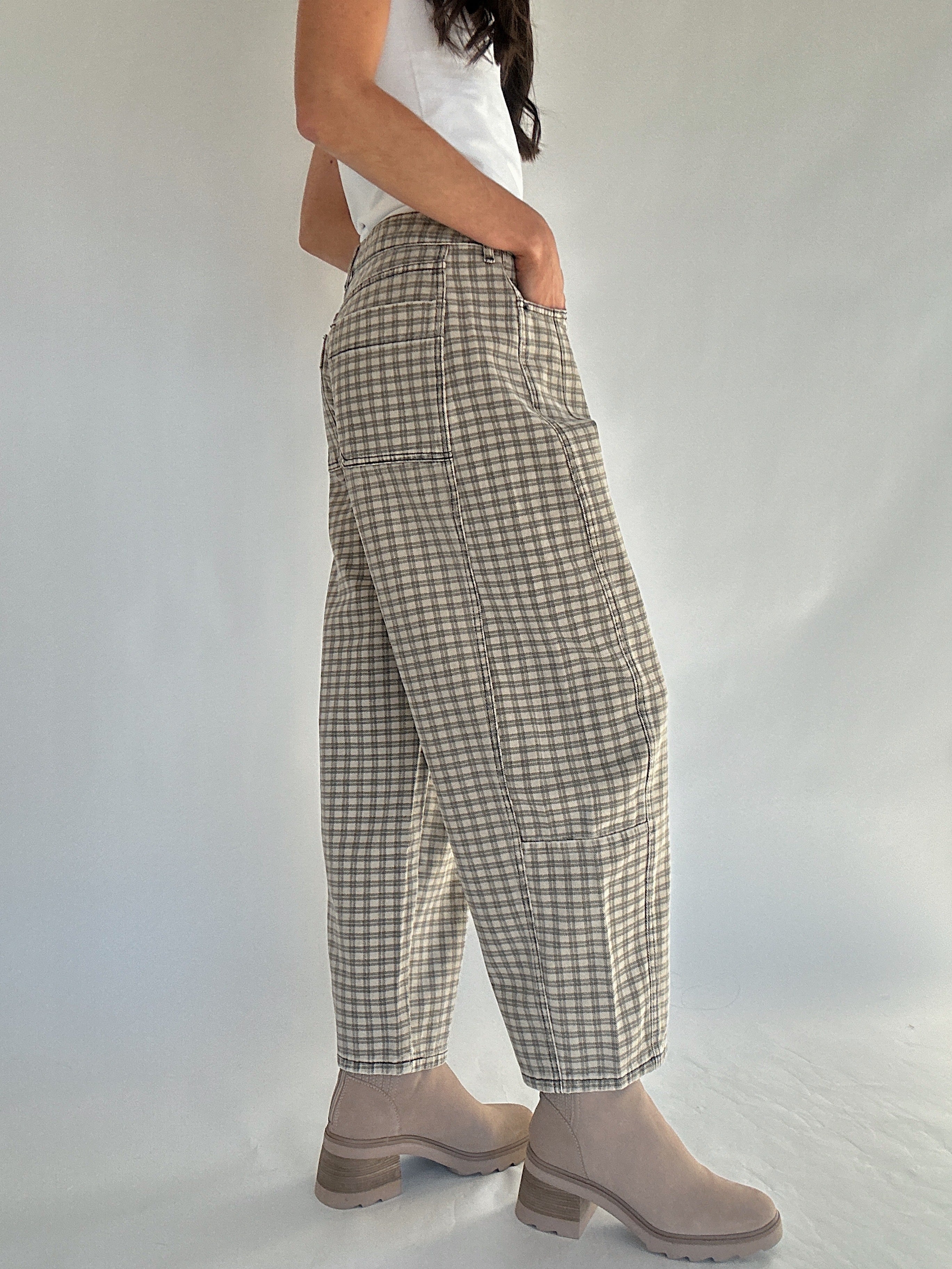 Person wearing plaid pants and beige boots on a plain background to show side