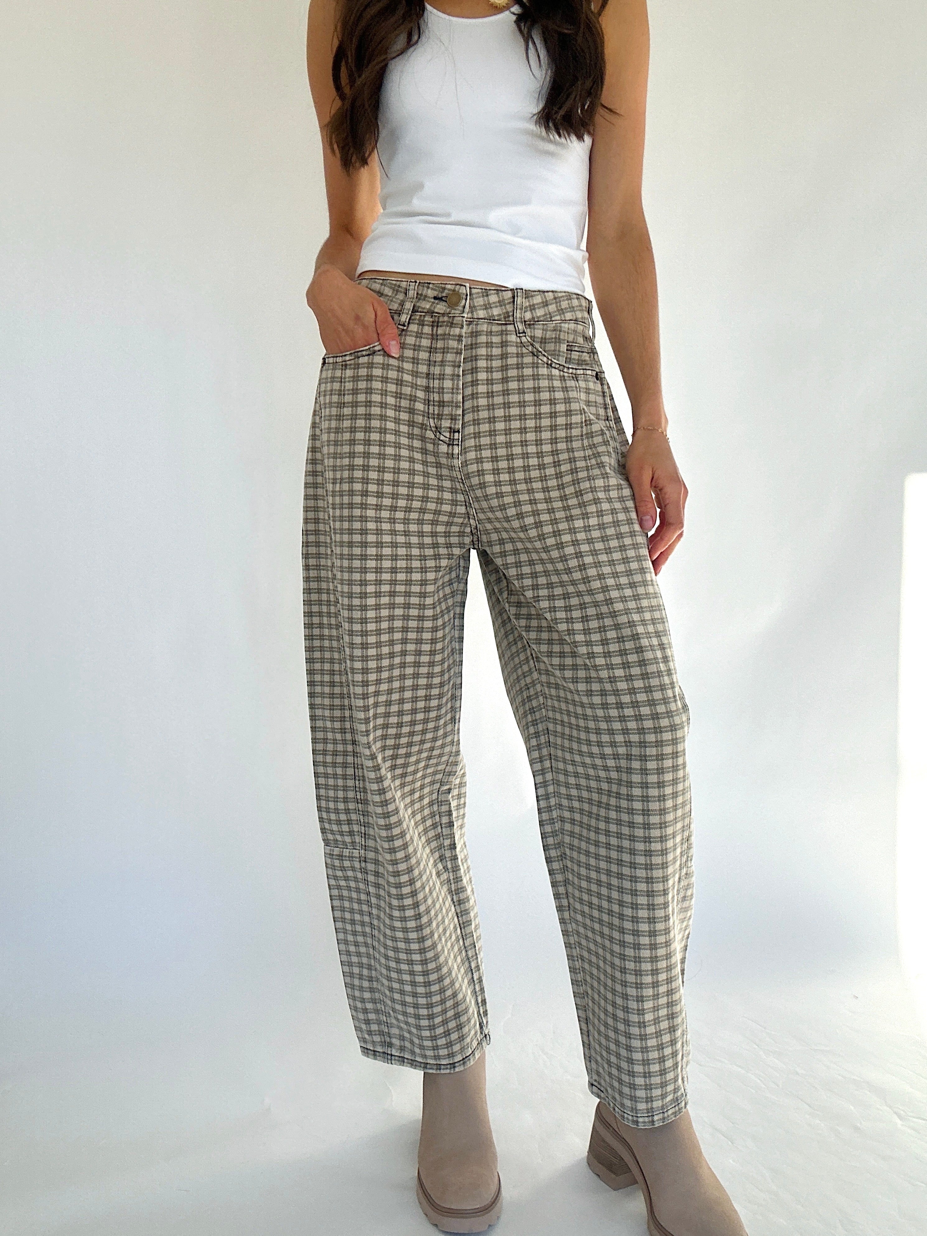 Person wearing plaid barrel pants and a white top on a white background