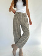 Person wearing plaid pants and a white top on a plain background