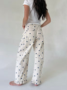 Person wearing white pants with navy polka dots on a plain background