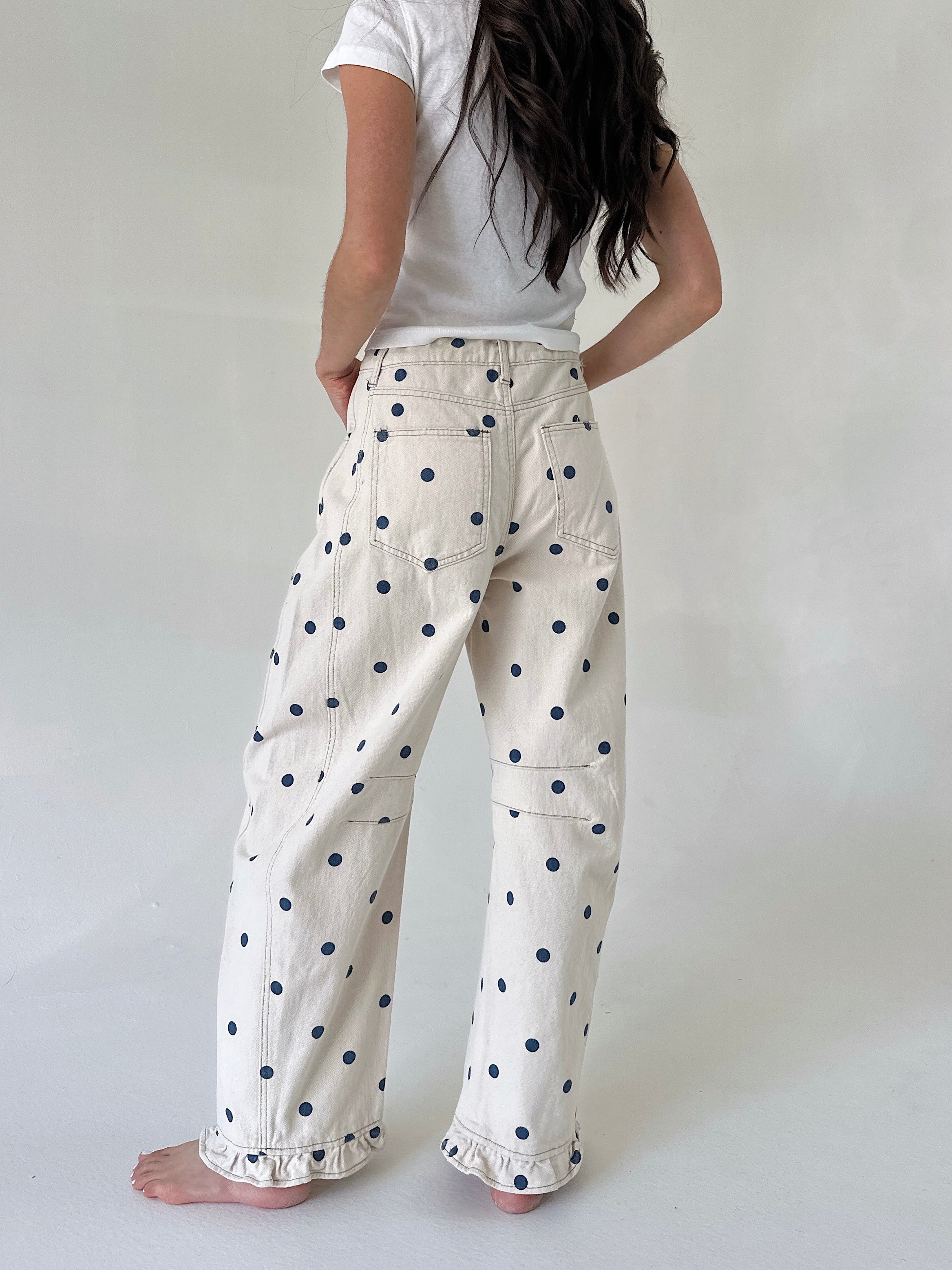 Person wearing white pants with navy polka dots on a plain background
