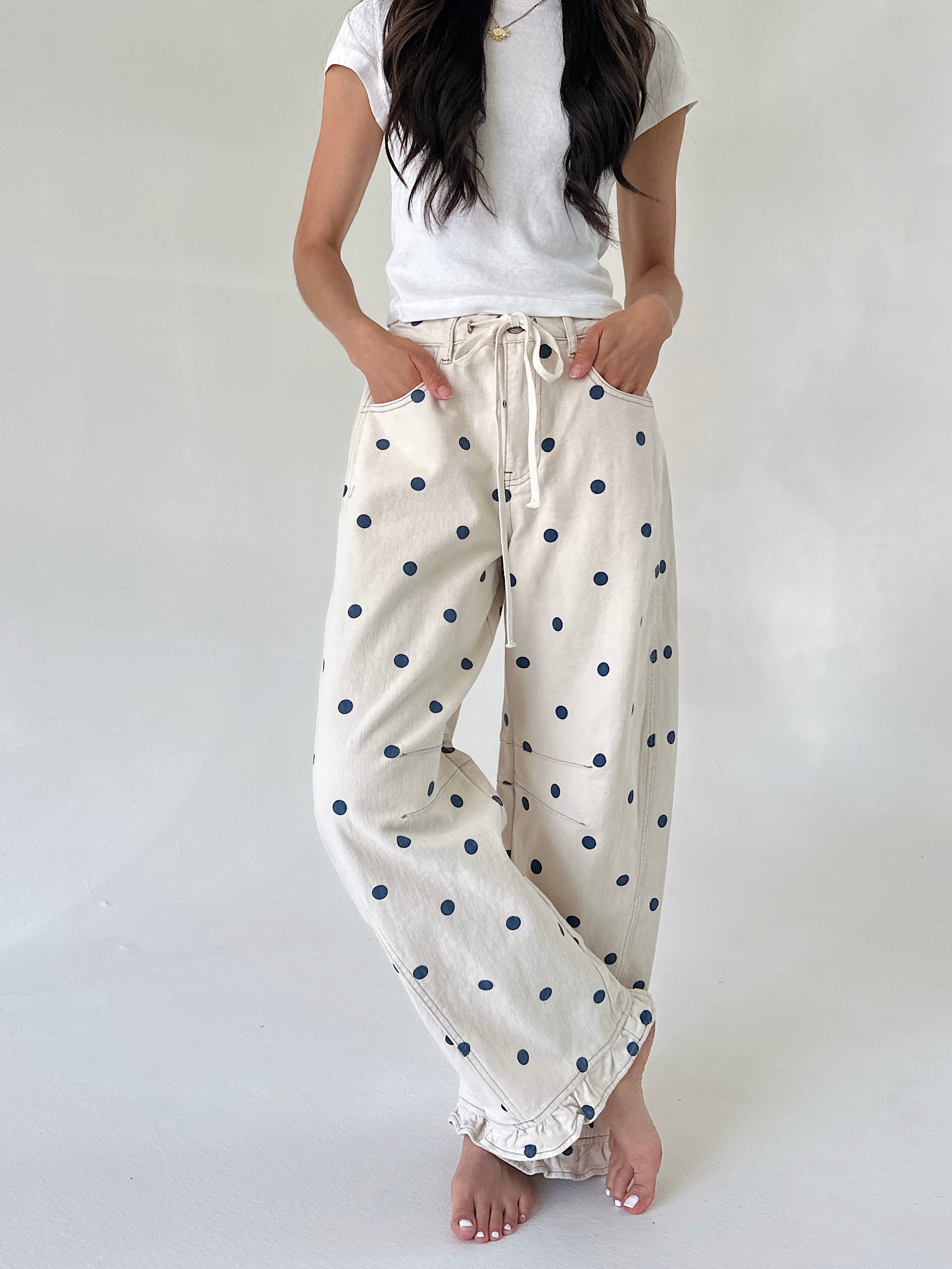 Person wearing white t-shirt and polka dot pants on a plain background