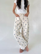 Person wearing white t-shirt and polka dot pants on a plain background