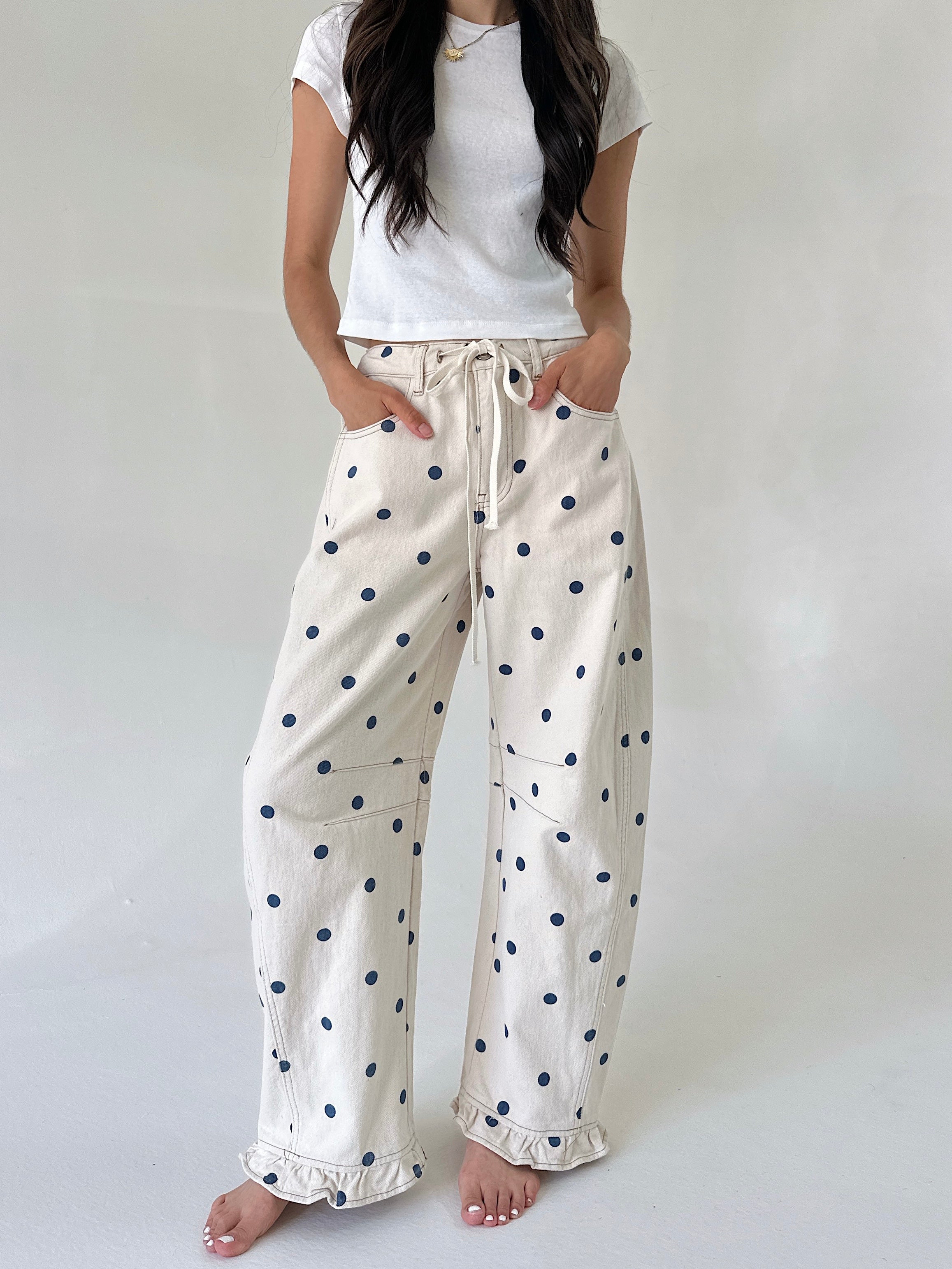 Woman wearing white t-shirt and polka dot pants on a plain background