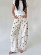 Woman wearing white t-shirt and polka dot pants on a plain background