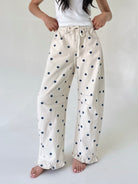 White pants with blue polka dots worn by a person on a white background
