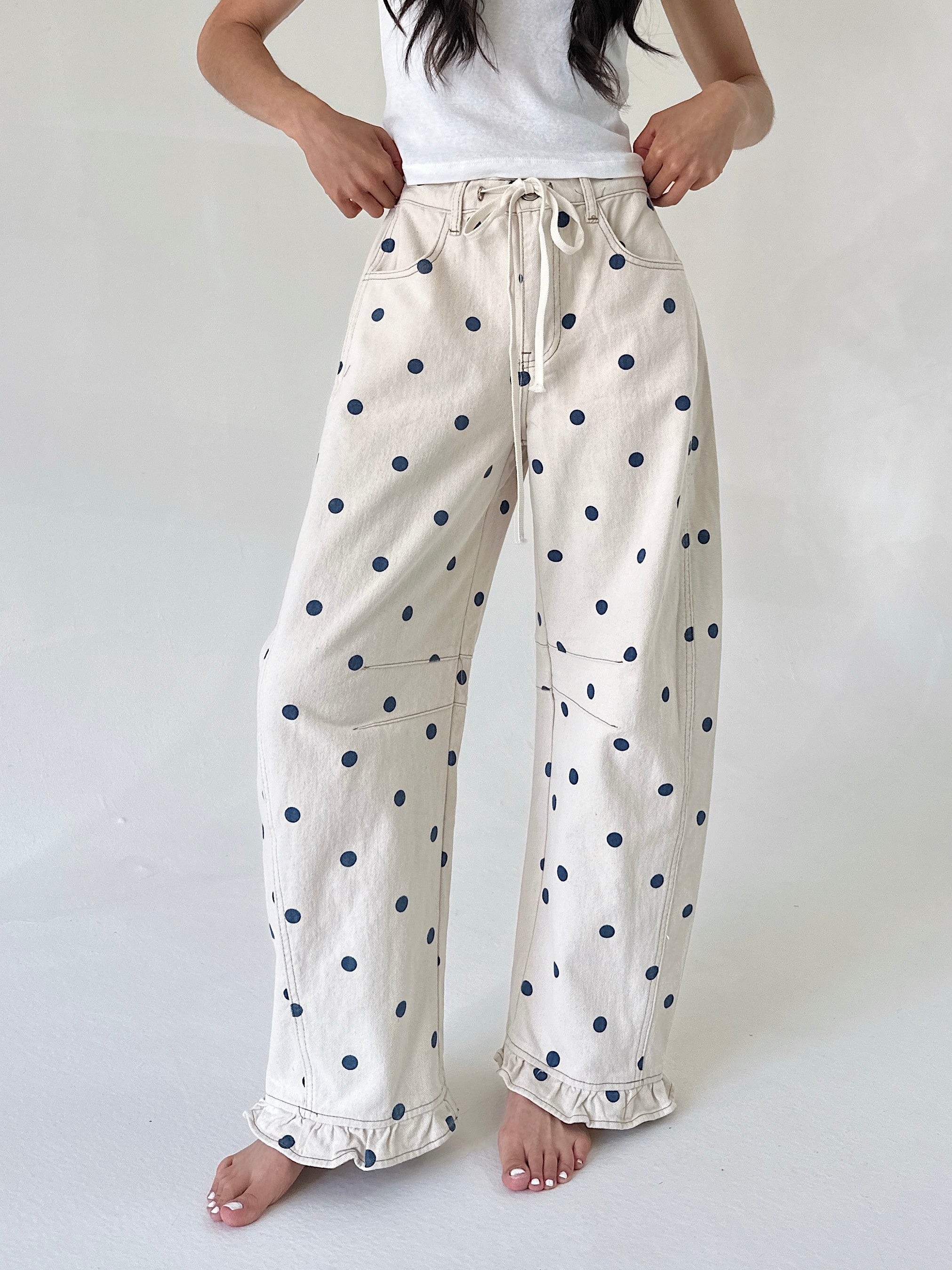 White pants with blue polka dots worn by a person on a white background