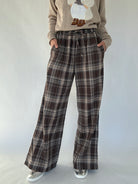 Brown plaid wide leg pants worn with a beige sweater on a white background