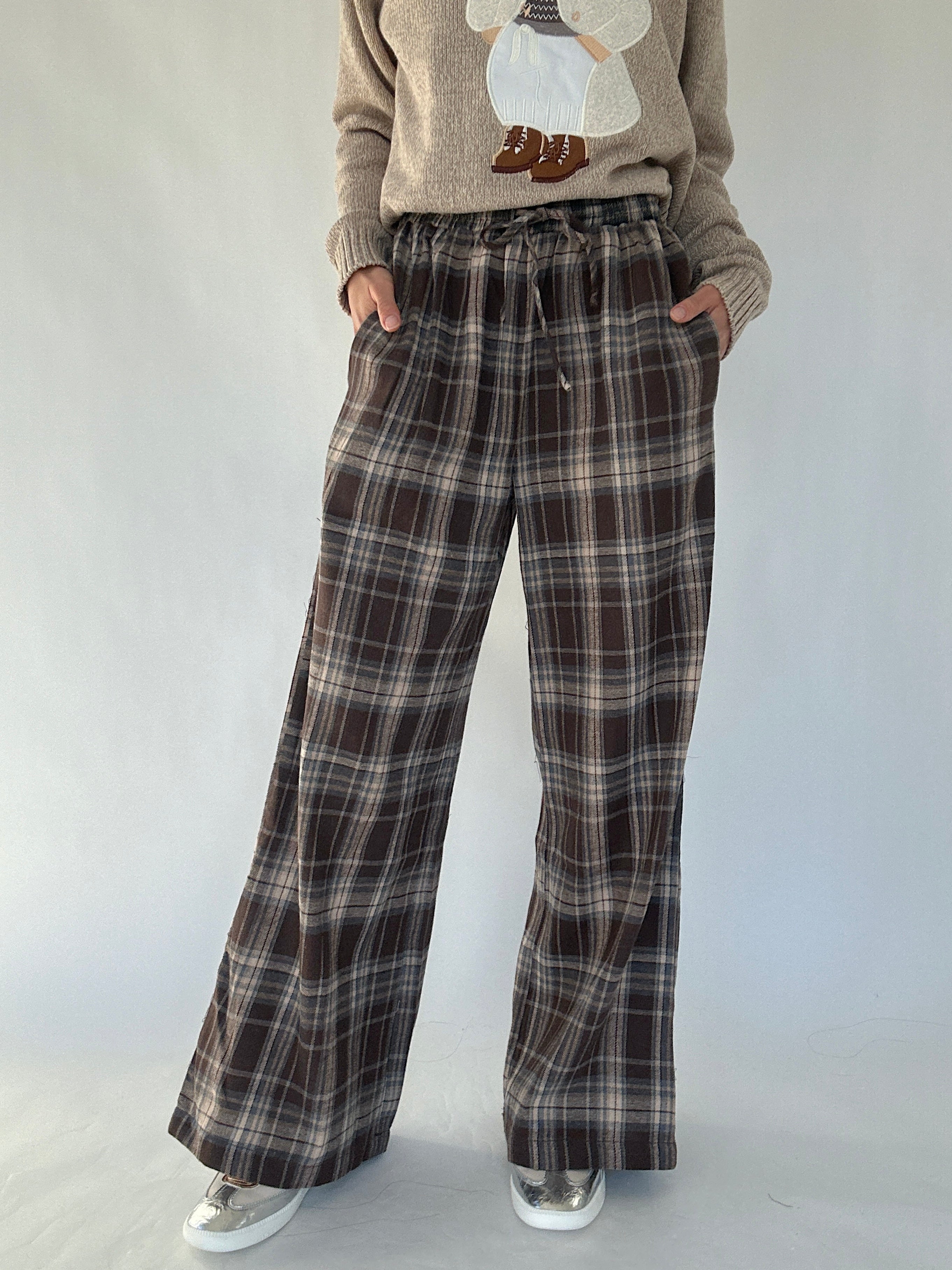 Brown plaid wide leg pants worn with a beige sweater on a white background