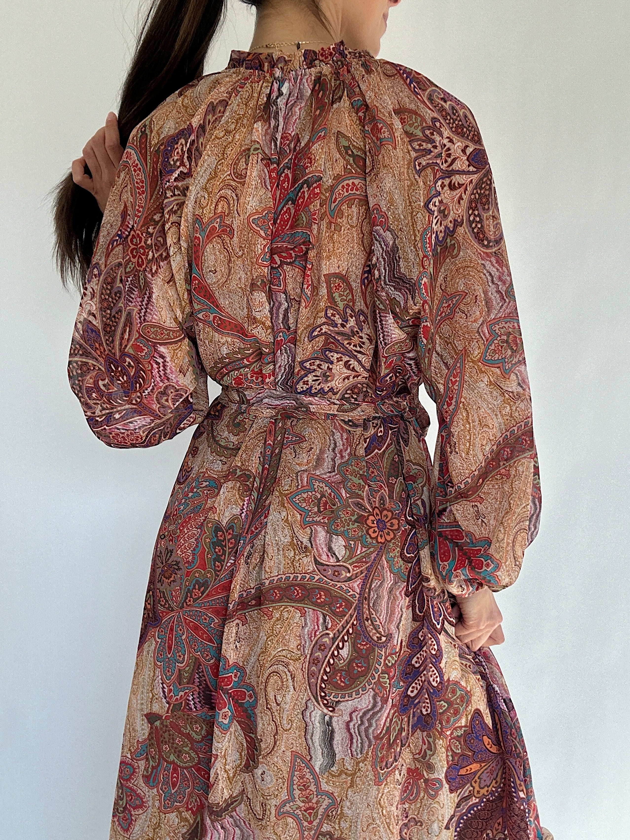 Patterned dress with long sleeves and a belt on a plain background showing back detail