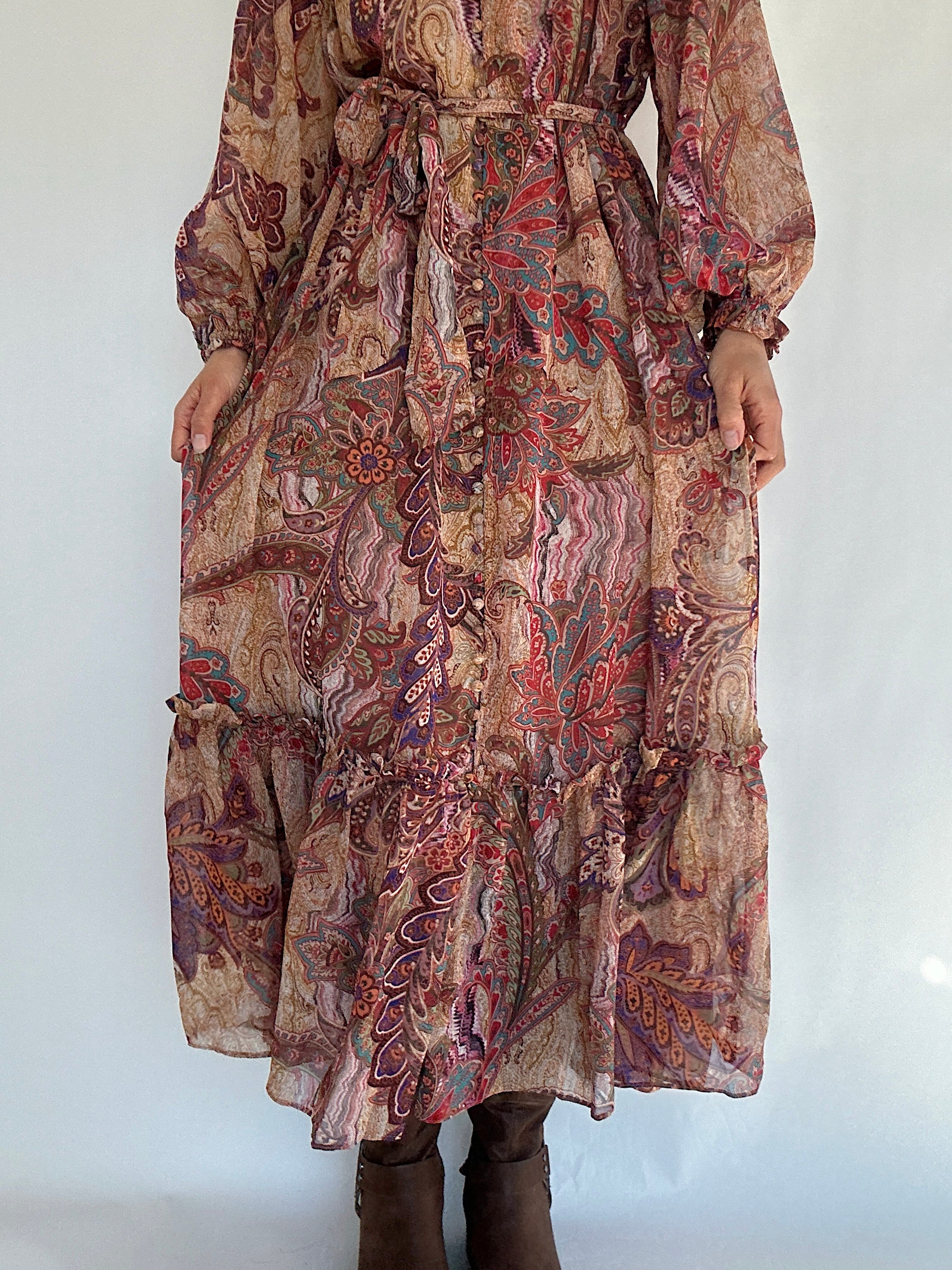 Bottom skirt of a long boho paisley patterned dress with a waist tie belt on a white background