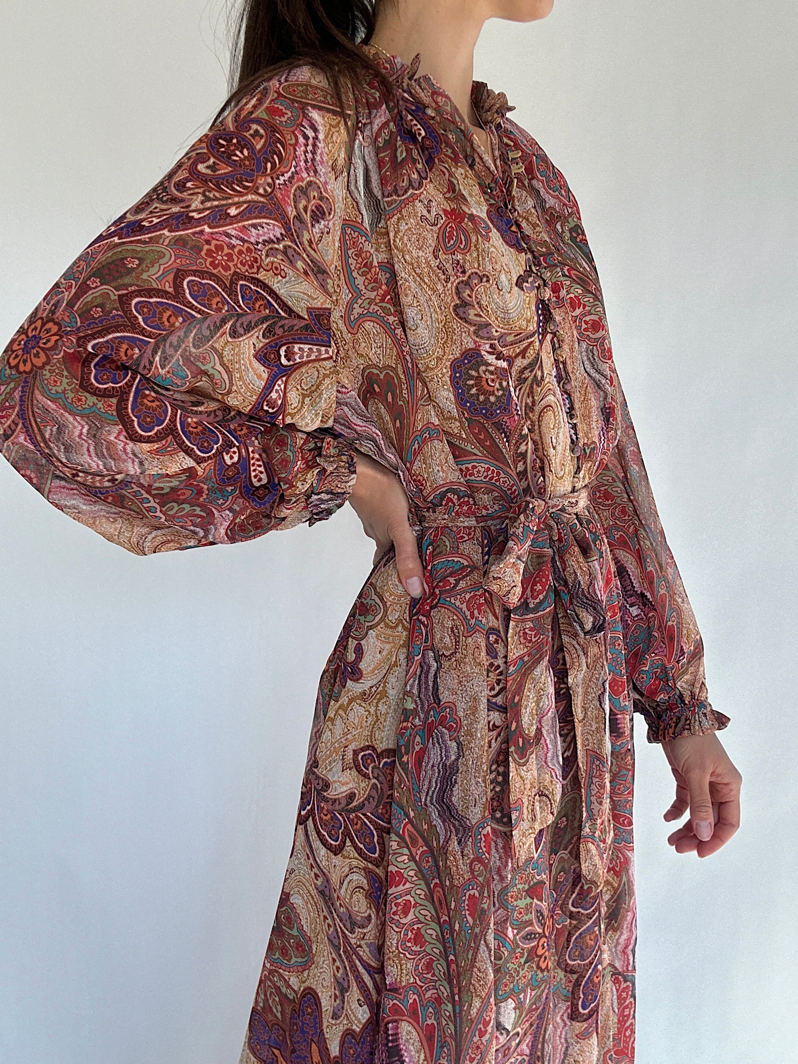 Boho paisley patterned dress with long sleeves and a belt on a plain background showing side detail