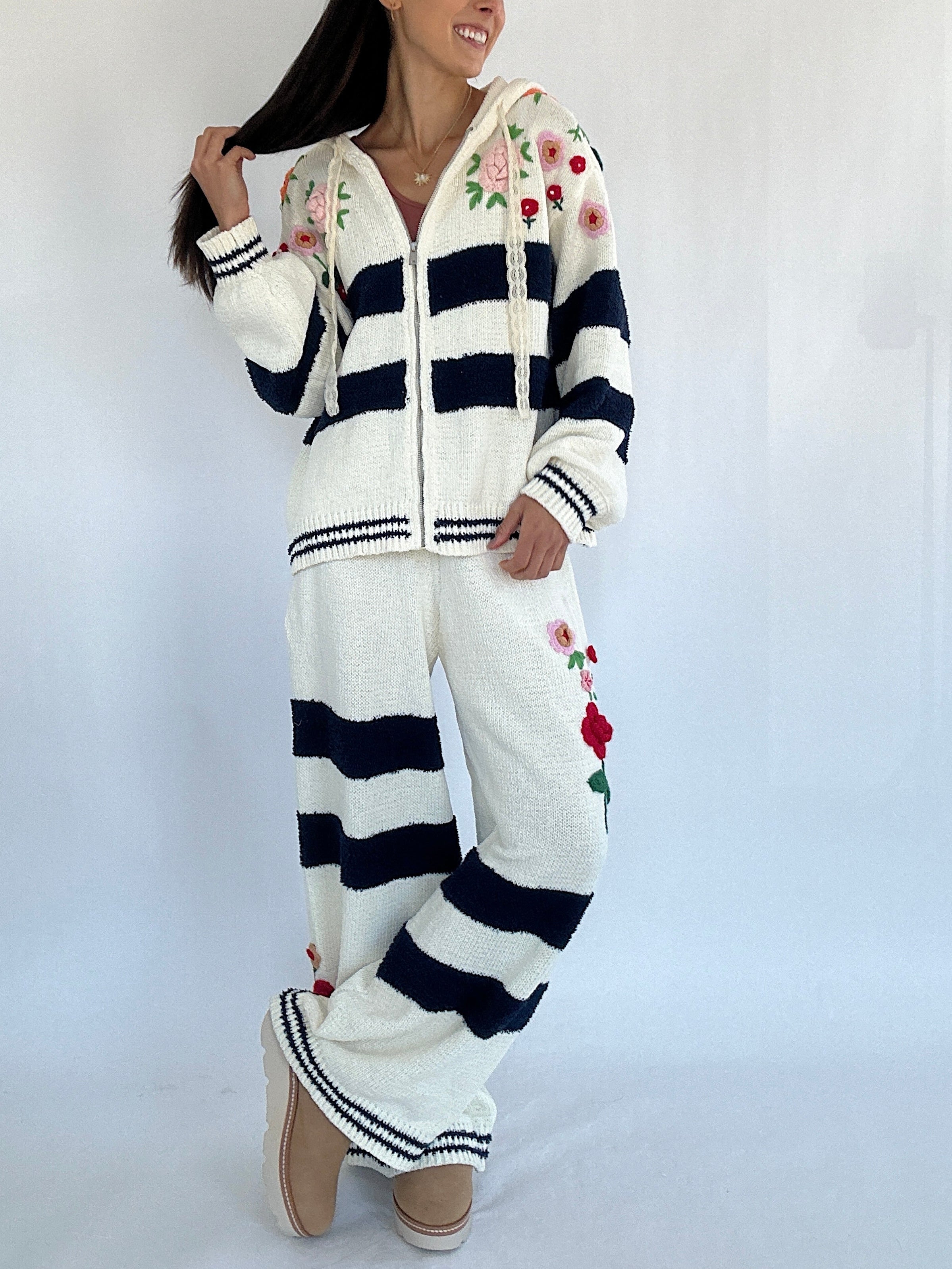 Person wearing a white and navy striped outfit with floral patterns on a plain background