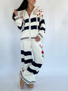 Person wearing a white and navy striped chenille outfit with floral patterns on a plain background