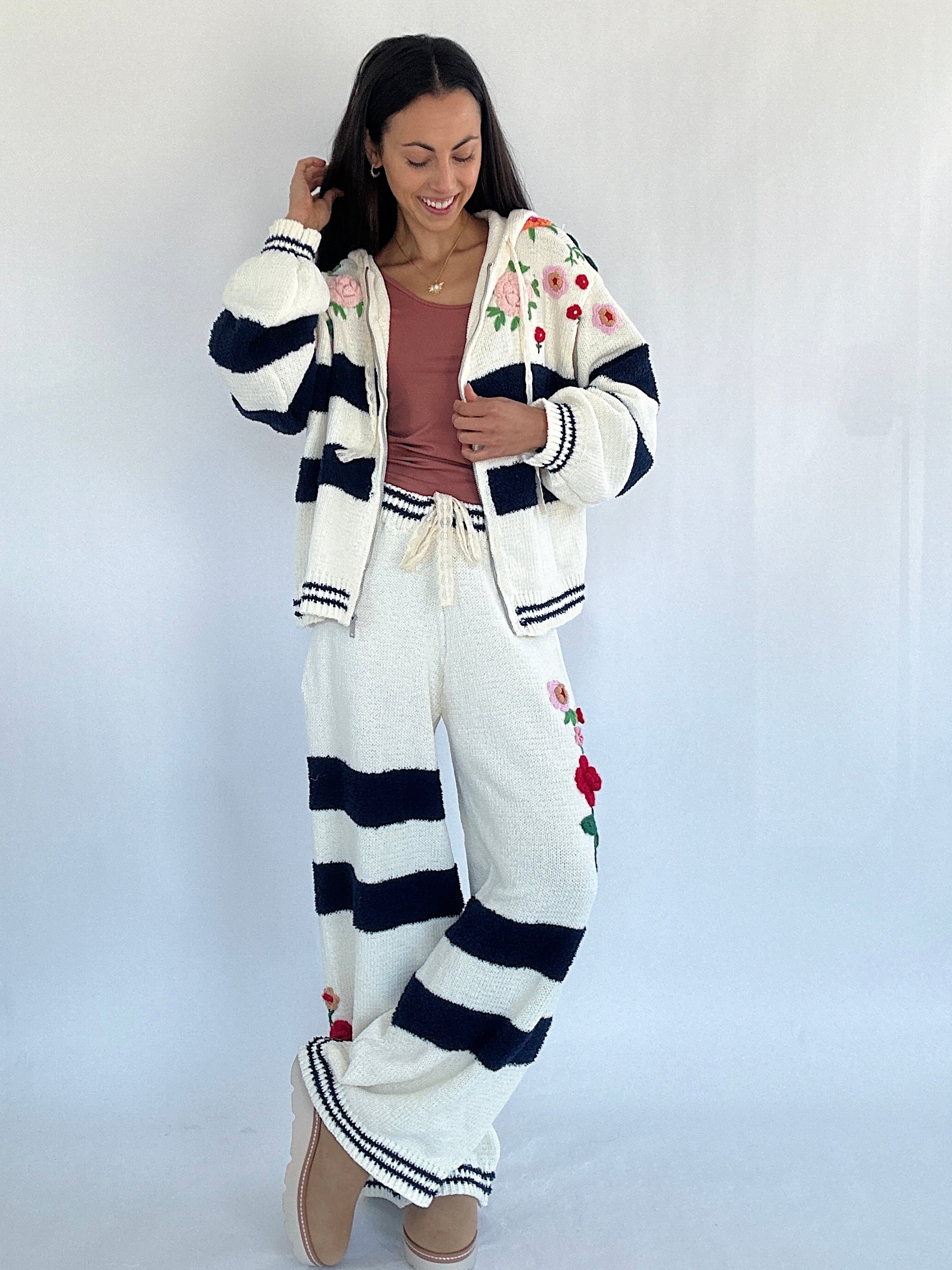 Woman wearing a white and navy striped cardigan with floral embroidery against a white background matching set