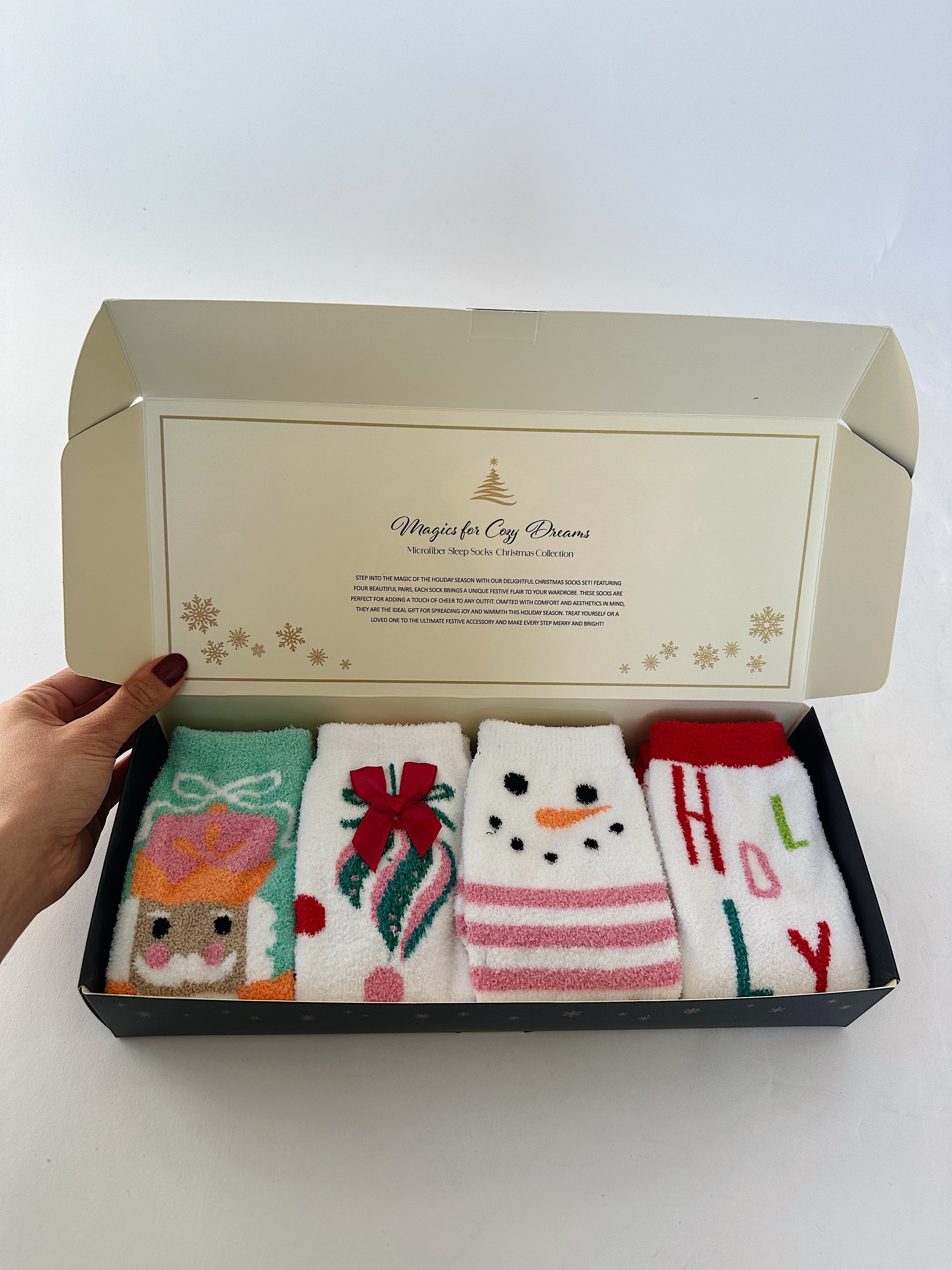 Set of four Christmas themed socks with designs in a decorative box on a white background