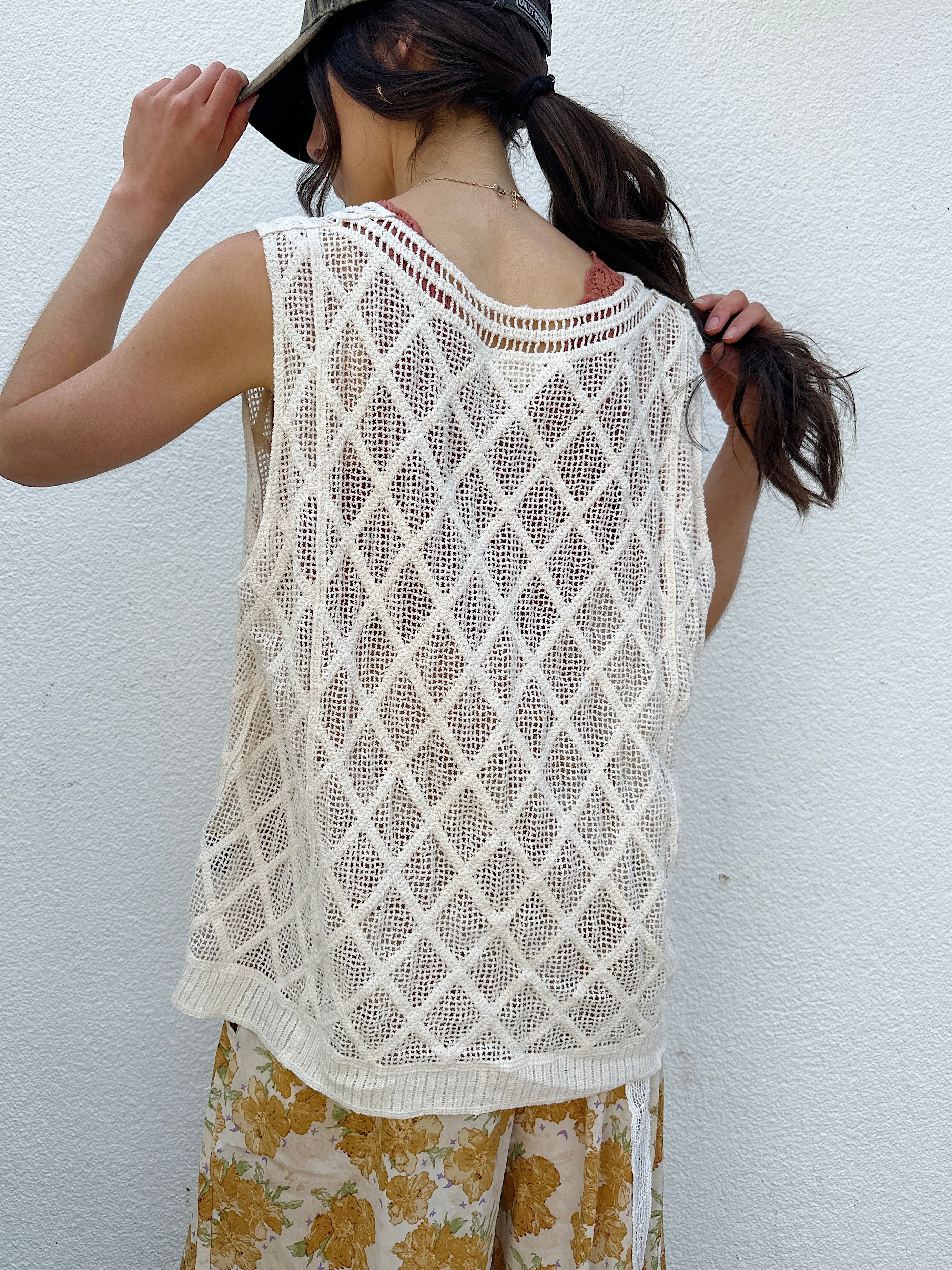 Person wearing a white crochet top against a white background