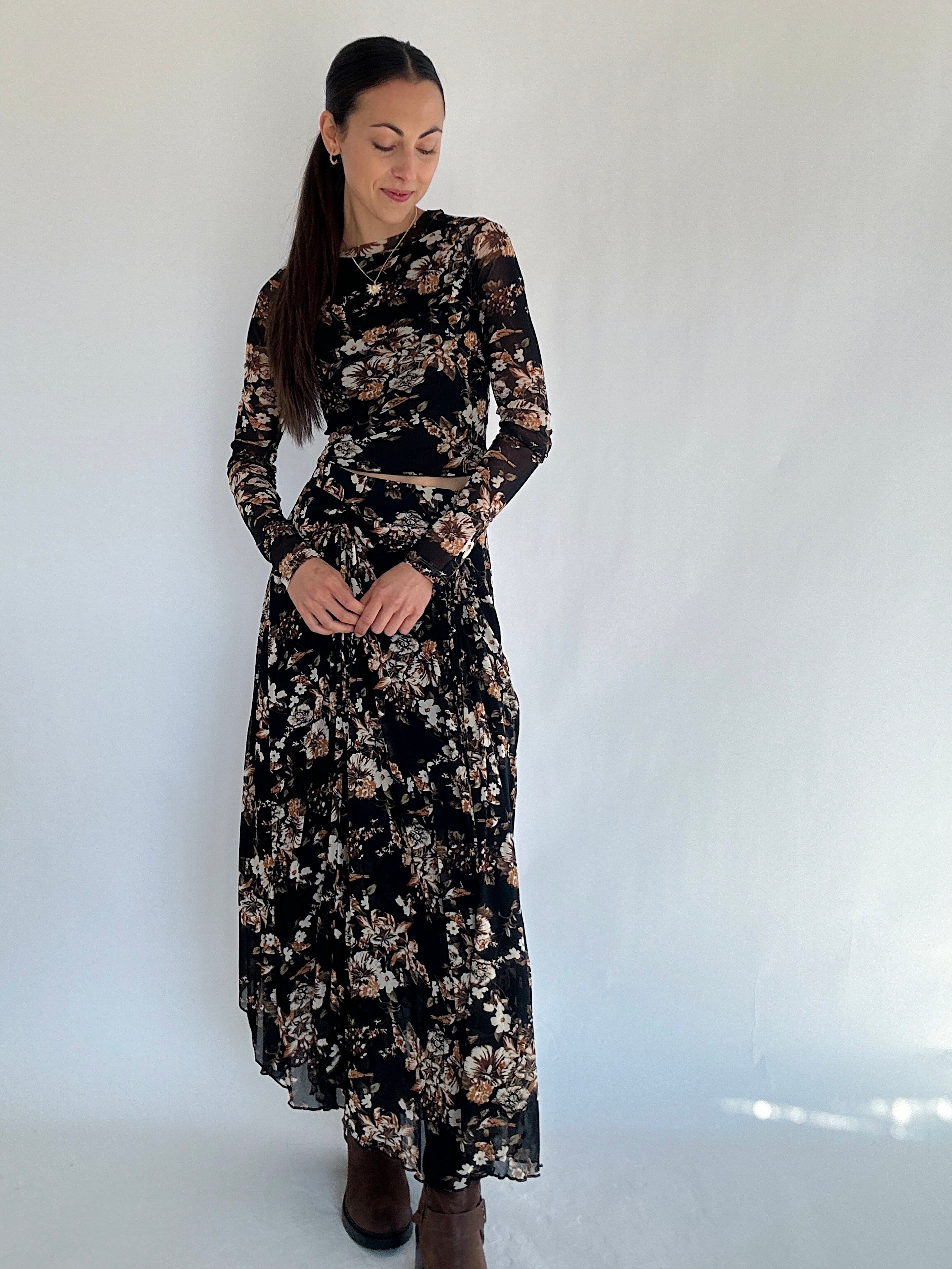 Woman wearing a long floral maxi skirt and matching long sleeve top against a white background