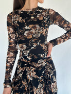 Woman wearing a black floral long sleeve top with matching skirt against a white background